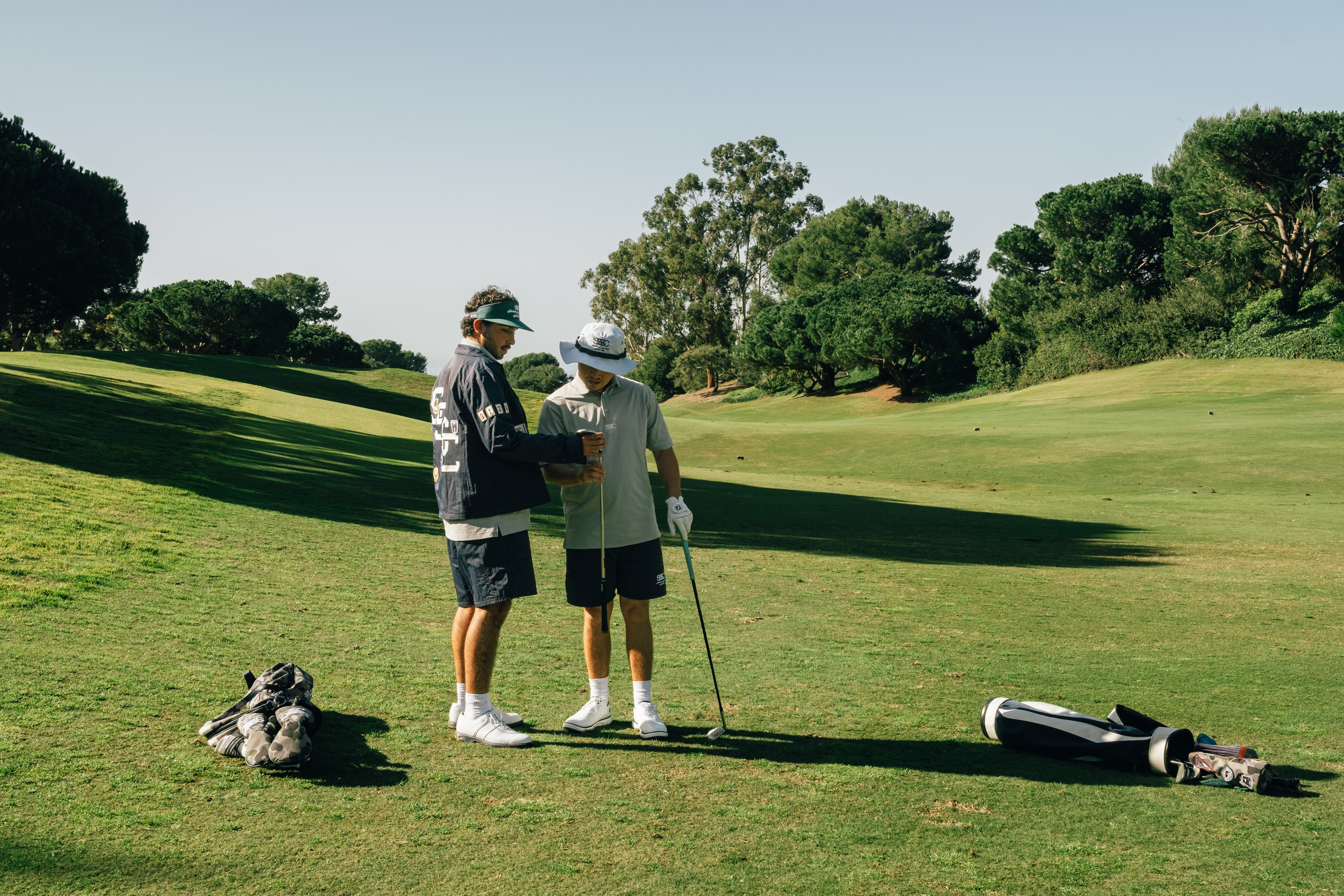 Two golfers on a green course with trees in the background