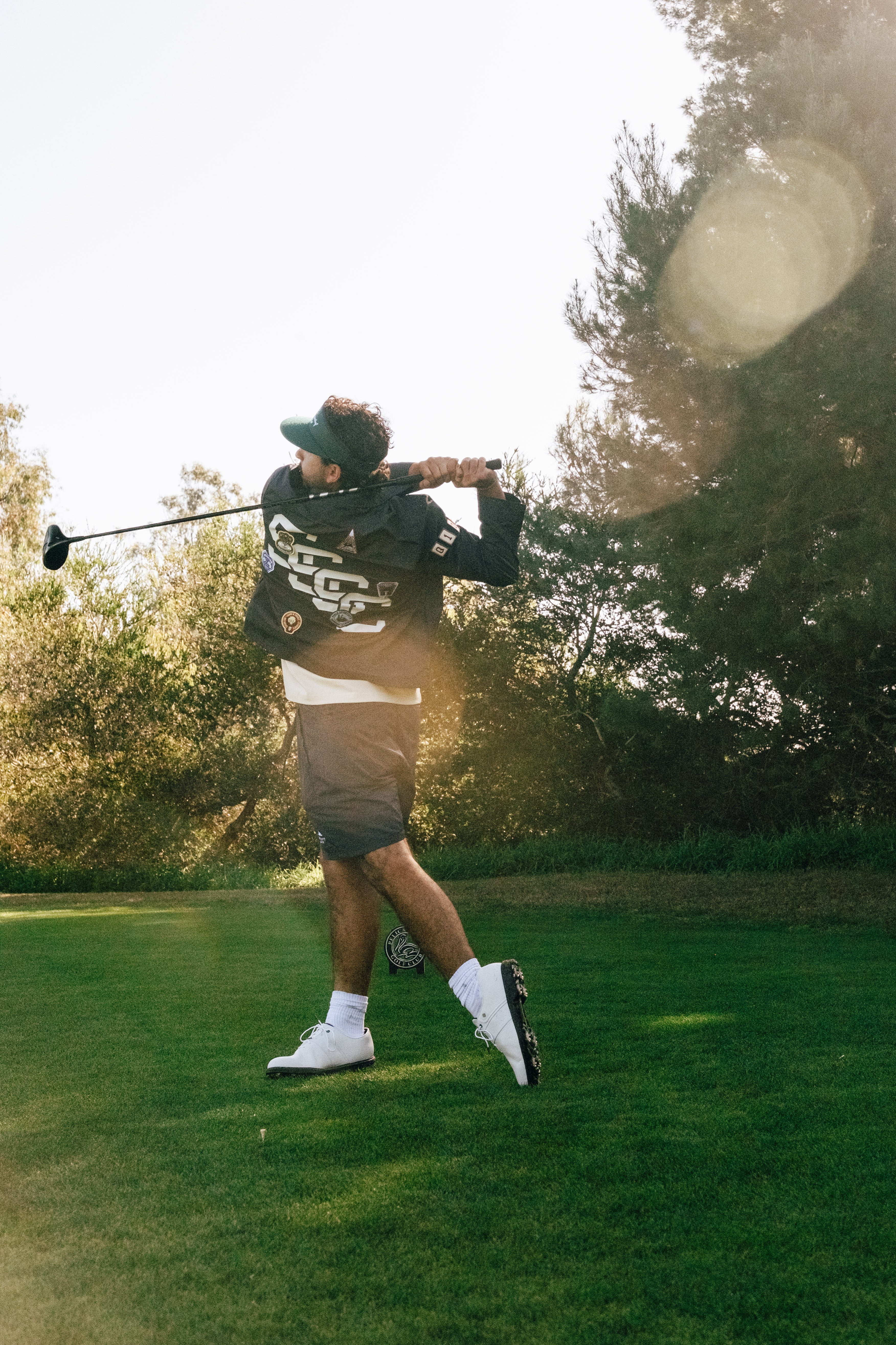 Person playing golf on a green course with trees in the background
