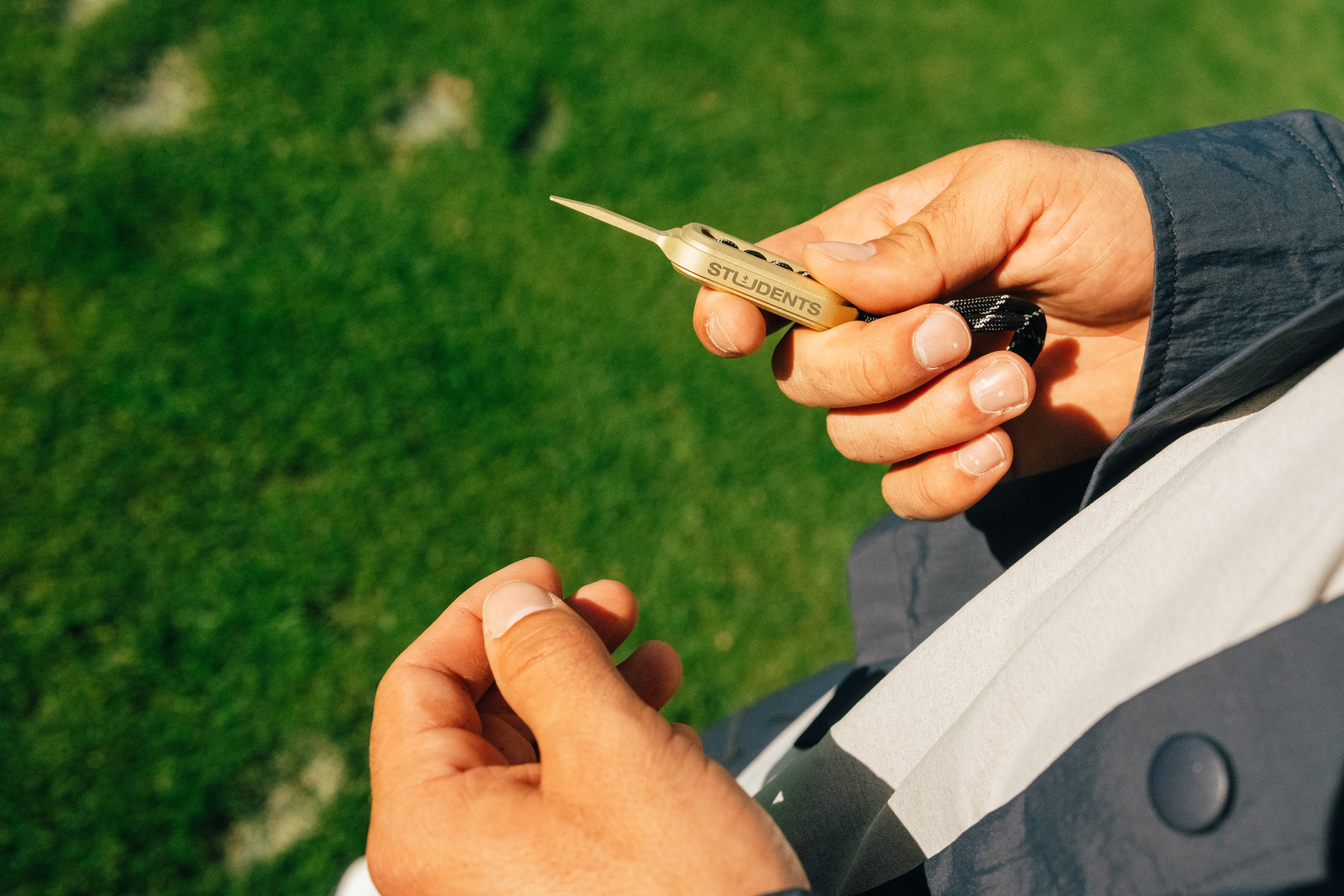 Person holding a small divot branding against a grassy background